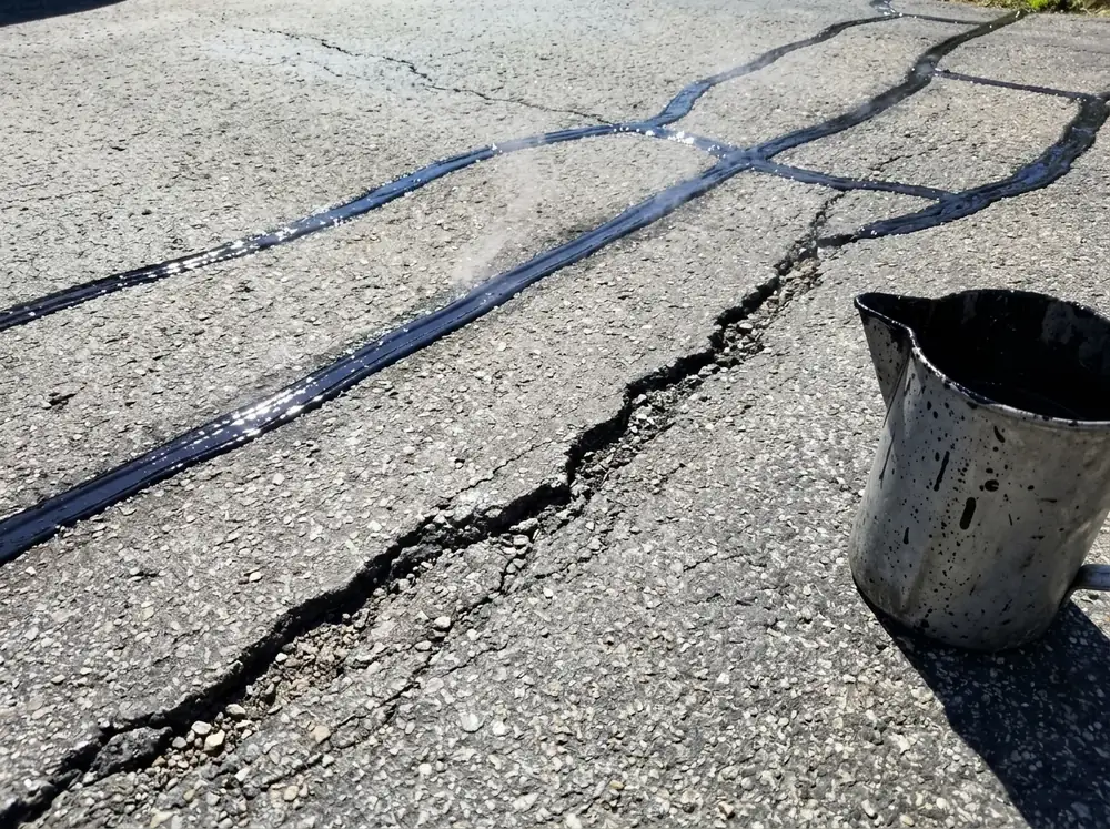 Cracks in an asphalt driveway filled with hot rubberized sealant